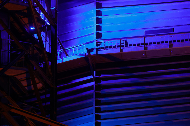 Die Außenhülle des Gasometers wird in zwei unterschiedlichen Blautönen angestahlt