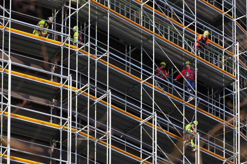 Sechs Gerüstbauer bei der Arbeit in großer Höhe.