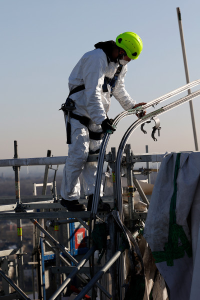 Gerüstbauer mit einer Führungsschine der Einhausung