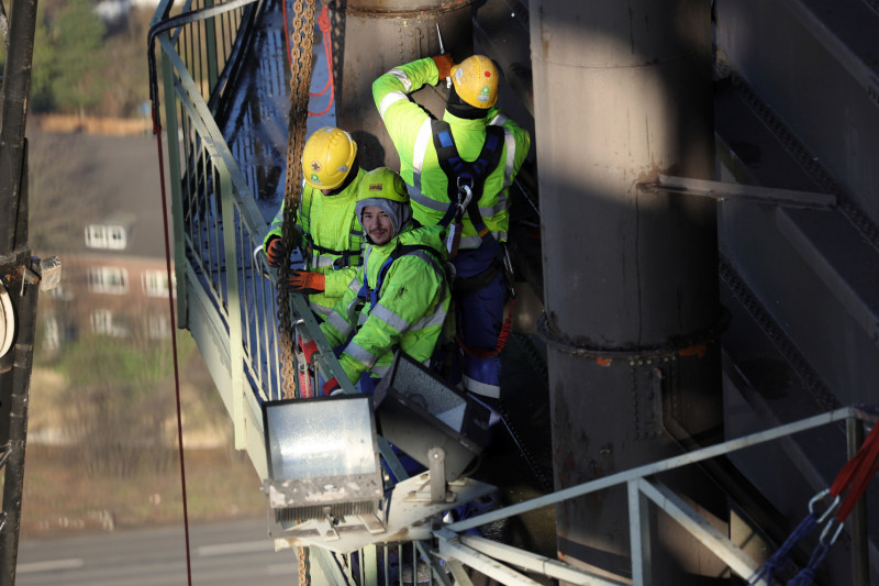 Drei Industriekletterer bei der Demontage eines Ausbläsers unterhalb der Dachkante des Gasometers.