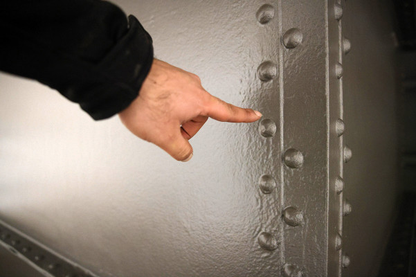 Ein Finger zeigt auf die Außenhülle des Gasometers mit der zweiten, grauen Zwischenschicht