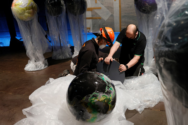 Zwei Mitarbeiter kontrollieren den Fuß eines Globusses