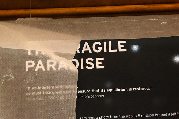 Das Foto zeigt den halb hinter Folie verborgenen Schriftzug "Das zerbrechliche Paradies" in englischer Sprache