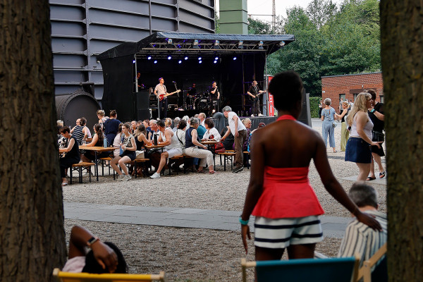 Die Bühne der Gruppe Mottek – davor – Bierzeltgarnituren mit der Musik genießenden Besucherinnen