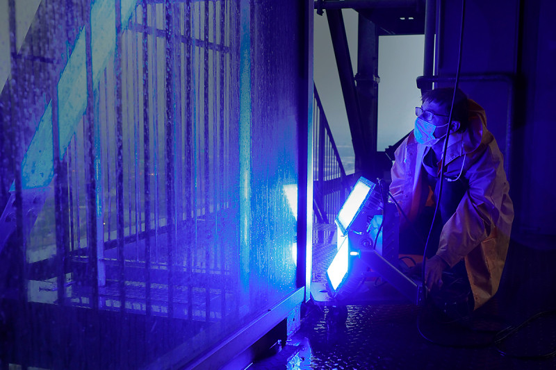 Ein Techniker richtet einen blauen Spor auf die Außenhülle des Gasometers