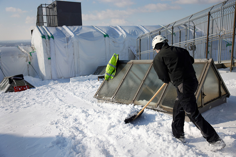 Arbeiter mit Schneeschaufel auf dem Dach des Gasometers